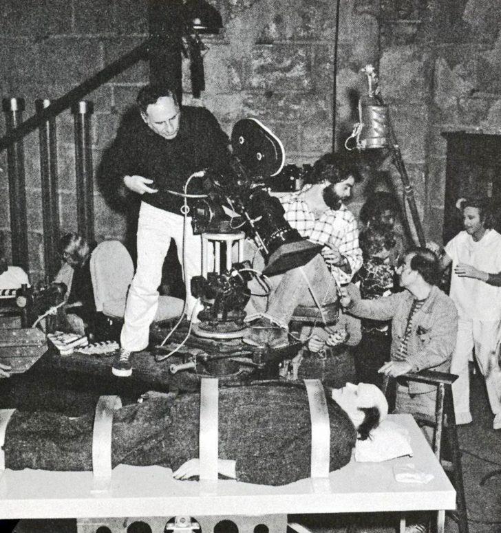 Shooting Young Frankenstein (1974), director Mel Brooks angles the camera on actor Peter Boyle as Hirschfeld (on ladder, at right) confers with his crew.