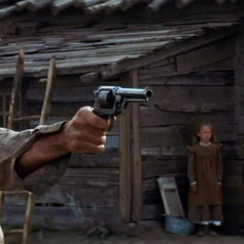Munny (Clint Eastwood) practices his marksmanship as his children look on.