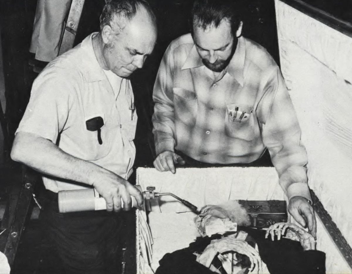 Jack Monroe and Henry Millar, Jr., from the special effects team, put some finishing touches on the remains of Beaufort Frankenstein with a blow torch. The will, leaving the estate to the new Dr. Frankenstein is in the metal box which will be placed in the skeletal hands of the corpse.